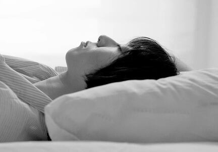 black and white image of woman sleeping on pillow