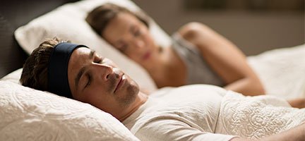 A couple lying in bed together asleep using SleepPhones as a sleeping pill alternative.