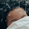 woman with covers over eyes sleeping to lullaby with music notes around head
