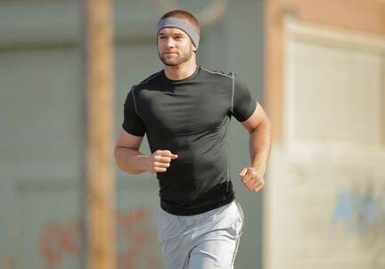 man in black fitness t-shirt and gray RunPhones headband headphones for running jogging