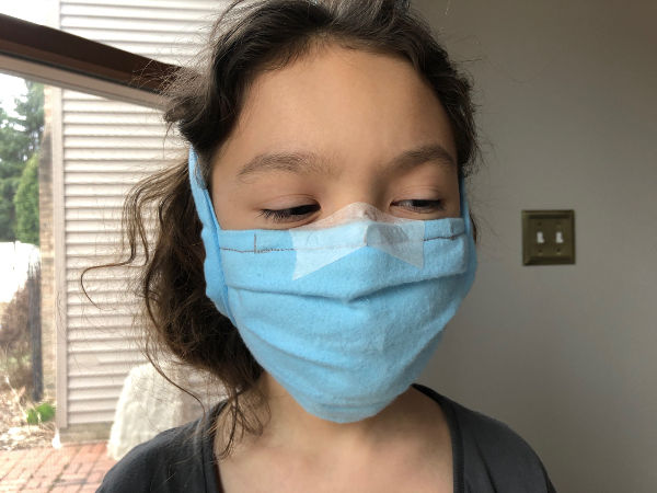 kid wearing a face mask comfortably secured with surgical tape
